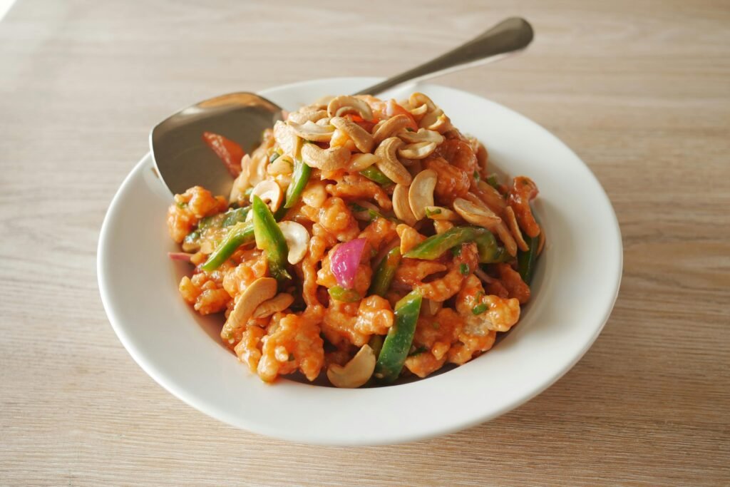 Delicious close-up of a cashew and vegetable stir-fry in a white bowl.
